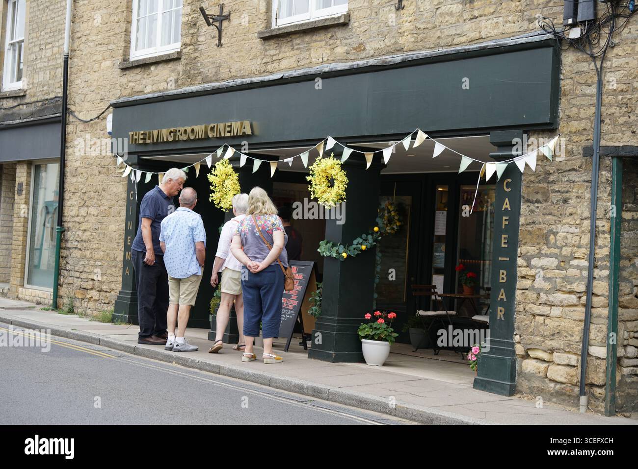 Gruppo di persone all'esterno di un piccolo Street Cafe e ingresso al cinema. Chipping Norton, Inghilterra Foto Stock