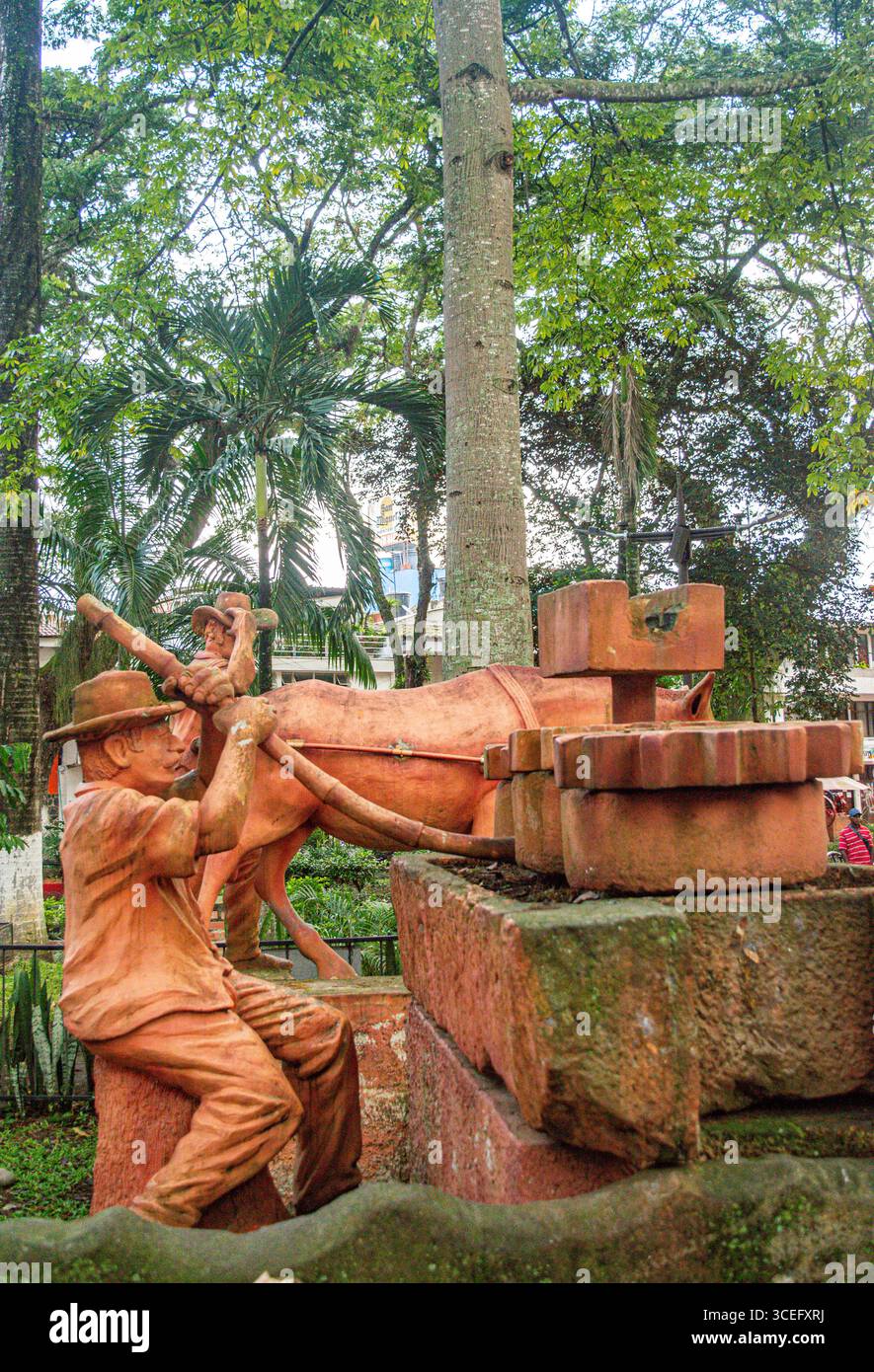 Una scultura artistica raffigurante un lavoratore che interagisce con i buoi, ambientata in un parco lussureggiante a Villeta, Cundinamarca, Colombia. Foto Stock