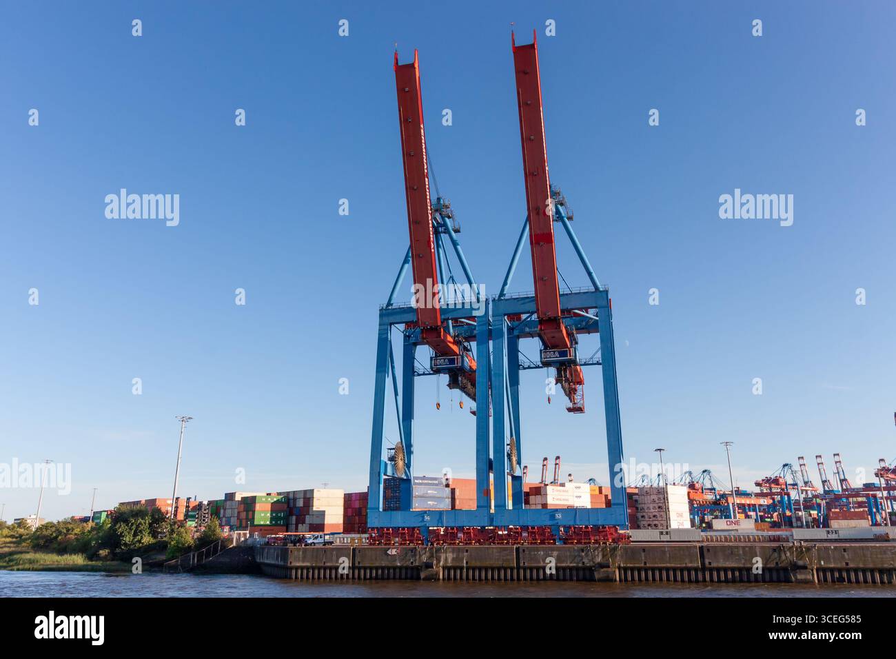 AMBURGO, GERMANIA - 12 AGOSTO 2024: Un'impressionante vista ad angolo basso di due massicce e moderne gru container nel porto di Amburgo Foto Stock