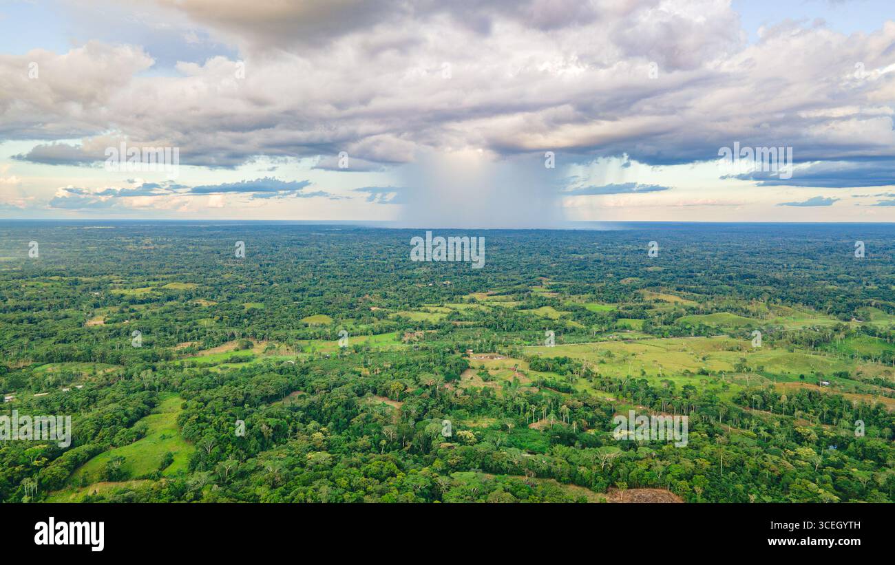 Splendida vista aerea che mostra il vibrante paesaggio verde di Putumayo, Colombia, con spettacolari formazioni nuvolose e pioggia in lontananza. Foto Stock