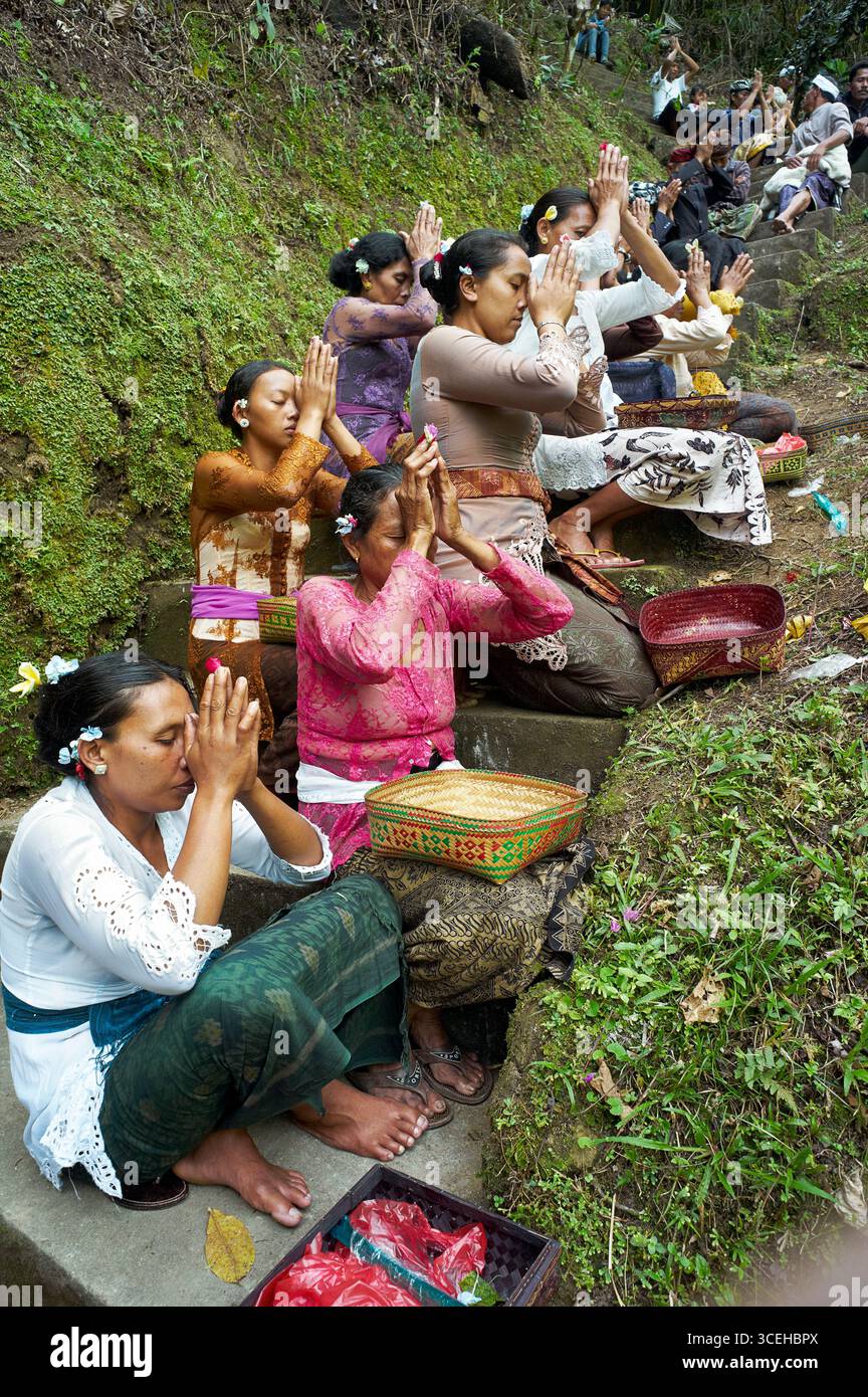 La gente del posto prega per un progetto di irrigazione dell'acqua dietro un sommo sacerdote indù balinese. La gente del posto ha portato offerte nella zona di preghiera. Foto Stock