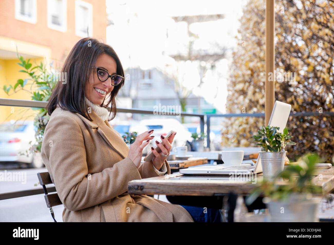 Donna d'affari che usa il telefono e il computer portatile all'aperto Foto Stock