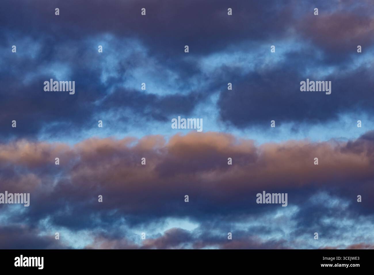 Nuvole serali colorate con sfumature di viola e arancione in un cielo crepuscolo Foto Stock