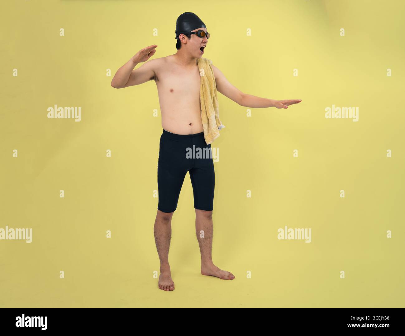 nuotatore sicuro che tiene in mano un asciugamano su sfondo giallo in studio Foto Stock