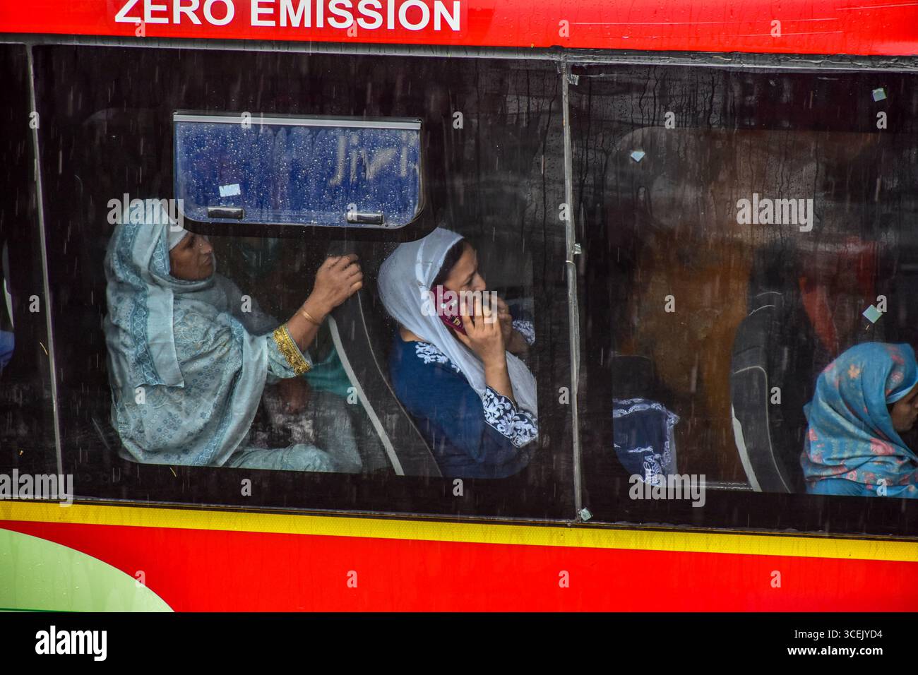 Srinagar, India. 18 agosto 2025. Le donne kashmiri vengono viste all'interno dell'autobus durante le precipitazioni a Srinagar. Almeno 67 persone sono state uccise e altre decine sono scomparse dopo due incidenti di pioggia torrenziale scatenata da nuvole nel Jammu e nel Kashmir. Nel frattempo, piogge da moderate a pesanti hanno attaccato ampie parti del Kashmir spingendo le autorità a istituire sale di controllo di emergenza in parti vulnerabili della valle, hanno detto i funzionari. Credito: SOPA Images Limited/Alamy Live News Foto Stock
