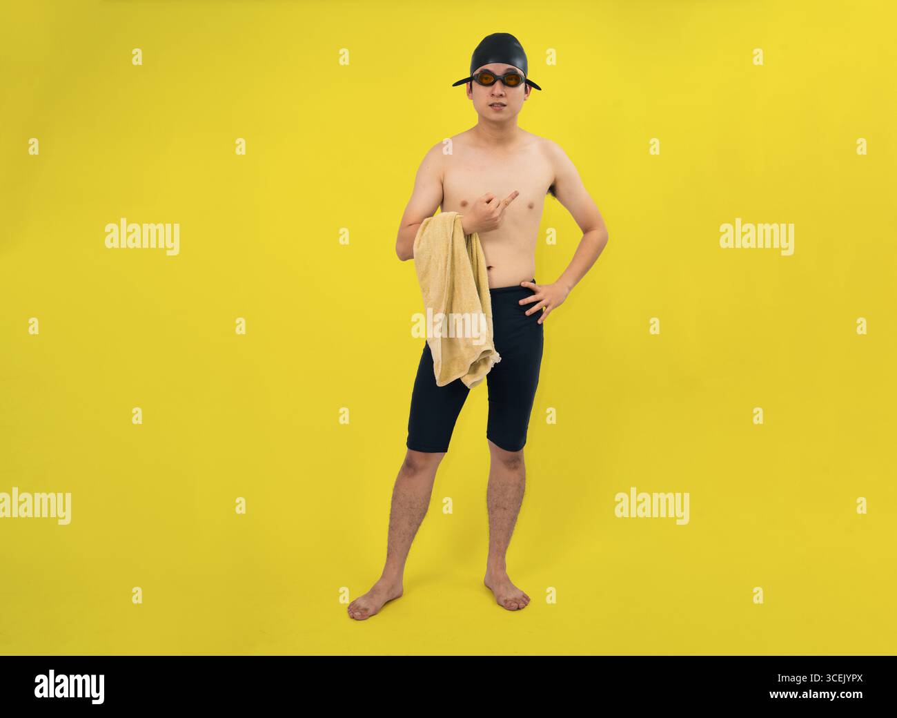 Il nuotatore in un abbigliamento professionale tiene in mano un asciugamano, posato con sicurezza su un suggestivo sfondo giallo Foto Stock