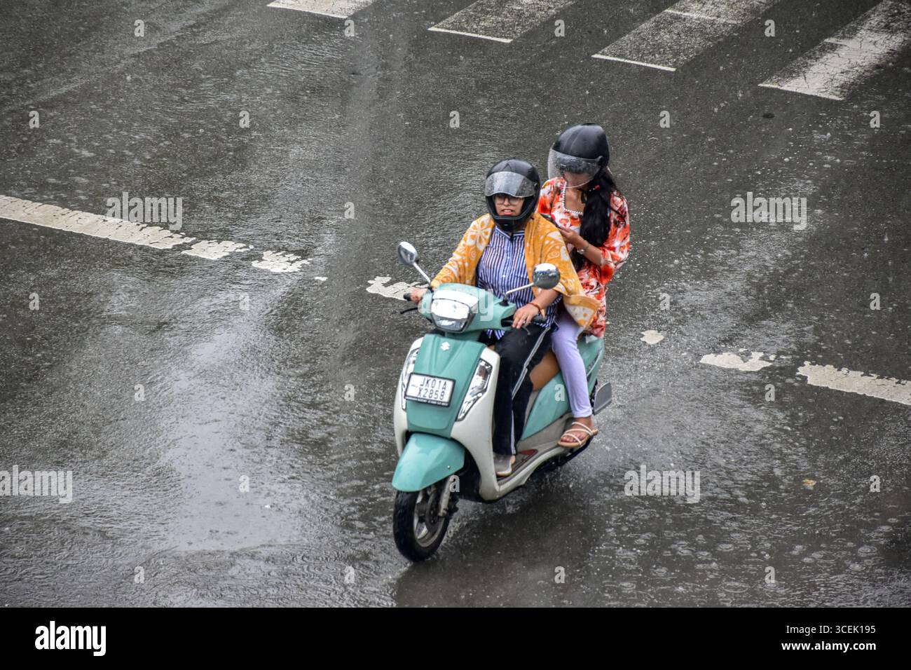 Srinagar, India. 18 agosto 2025. Una donna corre lungo la strada durante le piogge a Srinagar. Almeno 67 persone sono state uccise e altre decine sono scomparse dopo due incidenti di pioggia torrenziale scatenata da nuvole nel Jammu e nel Kashmir. Nel frattempo, piogge da moderate a pesanti hanno attaccato ampie parti del Kashmir spingendo le autorità a istituire sale di controllo di emergenza in parti vulnerabili della valle, hanno detto i funzionari. (Foto di Saqib Majeed/SOPA Images/Sipa USA) credito: SIPA USA/Alamy Live News Foto Stock