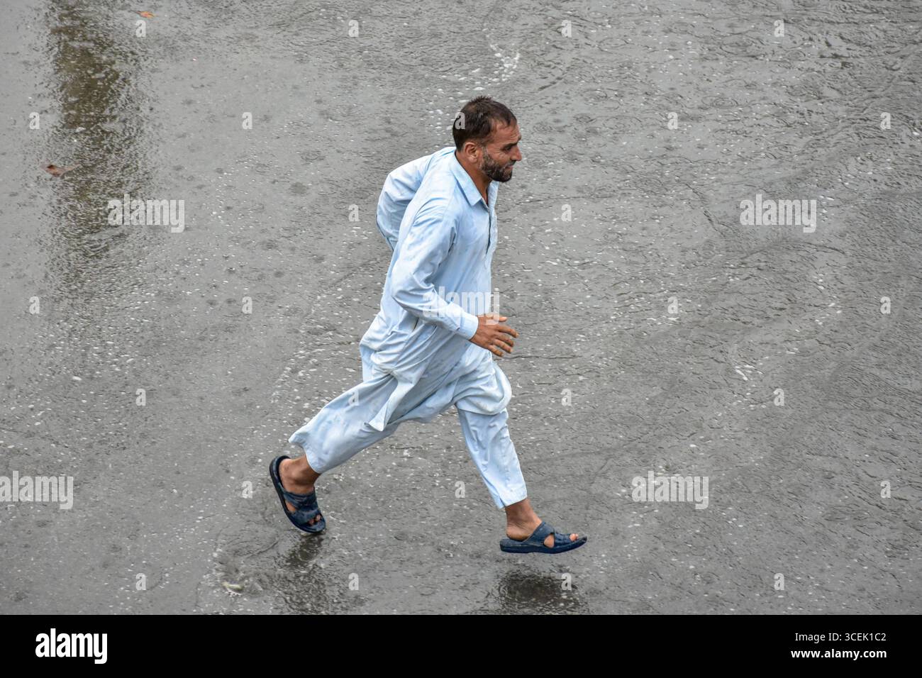 Srinagar, India. 18 agosto 2025. Un uomo corre verso il rifugio durante le piogge a Srinagar. Almeno 67 persone sono state uccise e altre decine sono scomparse dopo due incidenti di pioggia torrenziale scatenata da nuvole nel Jammu e nel Kashmir. Nel frattempo, piogge da moderate a pesanti hanno attaccato ampie parti del Kashmir spingendo le autorità a istituire sale di controllo di emergenza in parti vulnerabili della valle, hanno detto i funzionari. (Foto di Saqib Majeed/SOPA Images/Sipa USA) credito: SIPA USA/Alamy Live News Foto Stock