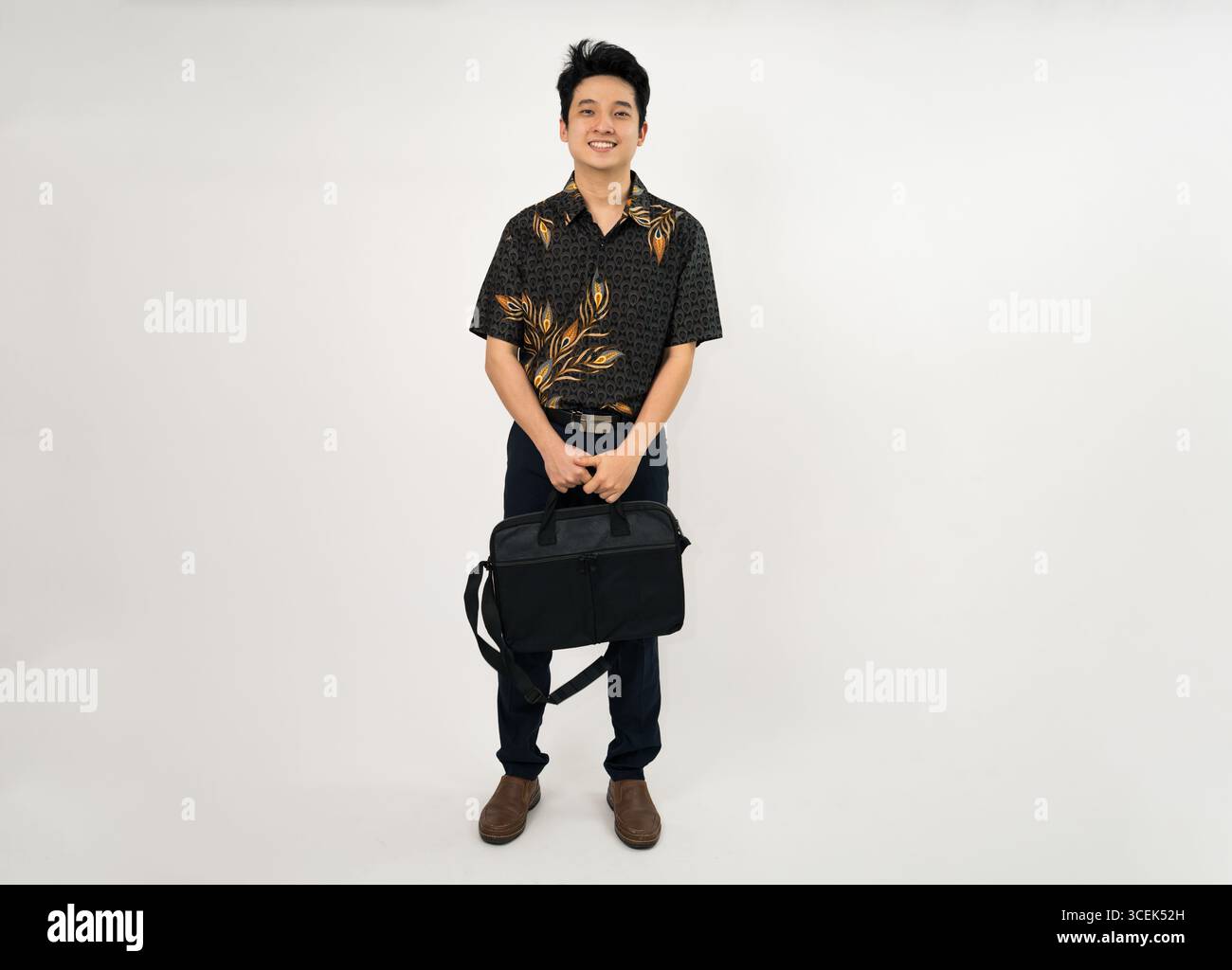 giovane professionista con una camicia batik che regge la valigetta in un abbigliamento casual da lavoro Foto Stock