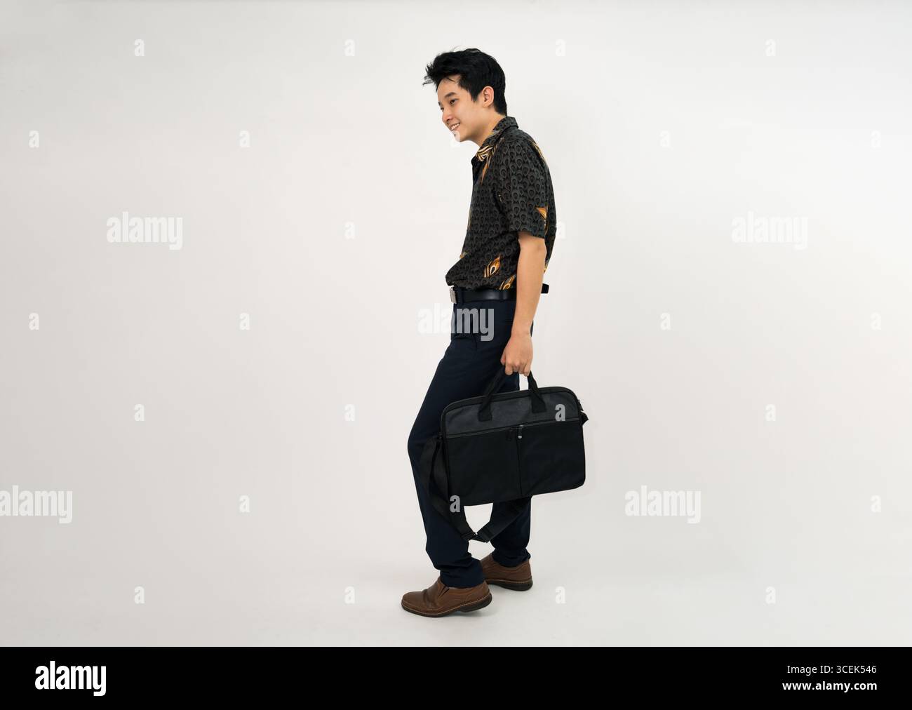 giovane professionista con una camicia batik che regge la valigetta in un abbigliamento casual da lavoro Foto Stock