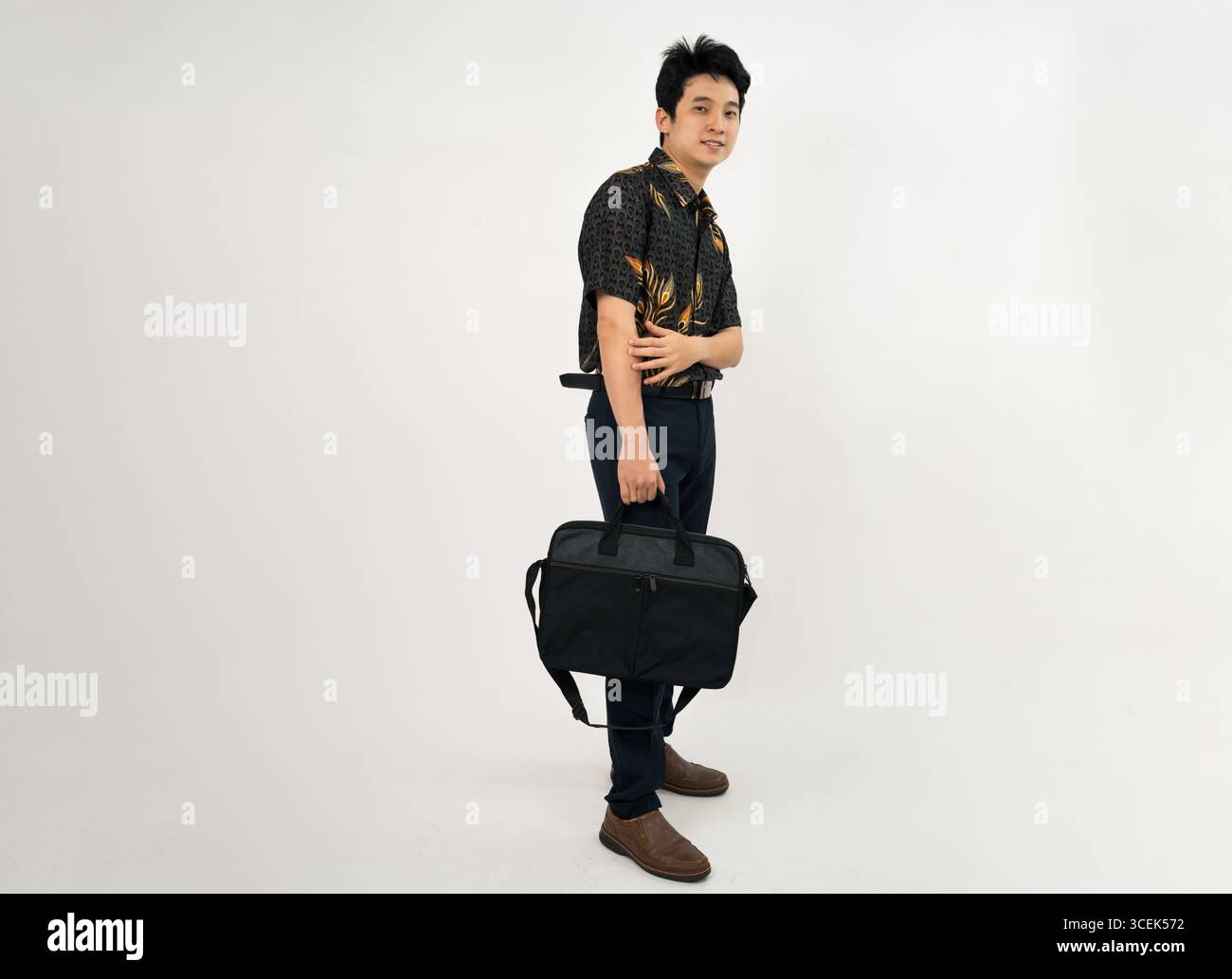 giovane professionista con una camicia batik che regge la valigetta in un abbigliamento casual da lavoro Foto Stock