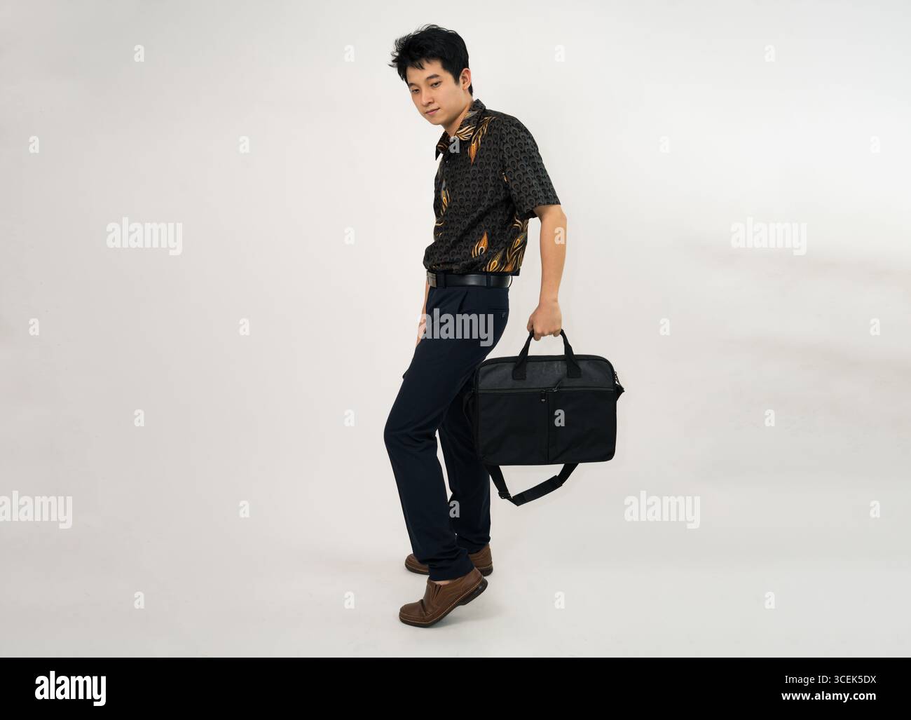 giovane professionista con una camicia batik che regge la valigetta in un abbigliamento casual da lavoro Foto Stock