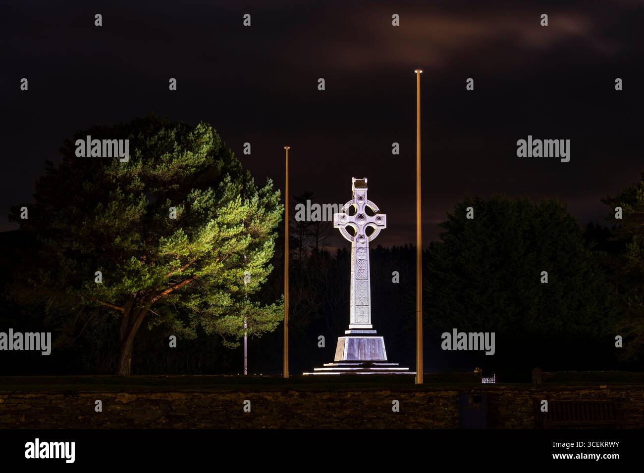 Questa fotografia notturna mostra un monumento a croce celtica splendidamente illuminato, alto contro un cielo scuro. Foto Stock