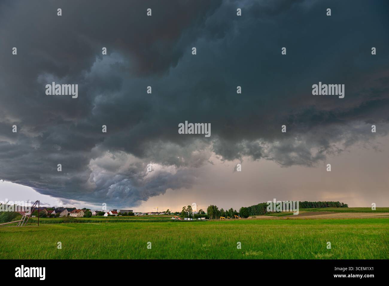 Il cielo scuro contrasta nettamente con un campo verde brillante mentre il bordo di una tempesta si sposta sulla campagna in Baviera, Germania Foto Stock