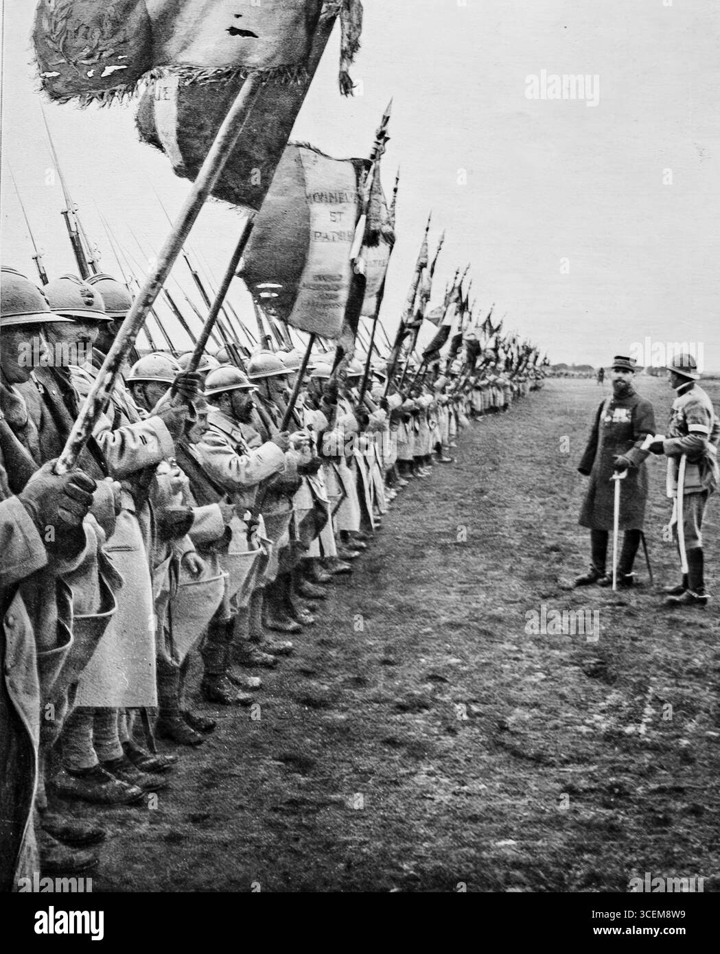 1916 maggio, prima guerra mondiale: Il generale Gouraud ispeziona una grande parata di bandiere del reggimento per onorare una divisione francese distinta a Verdun. I soldati sono in formazione con fucili e striscioni, simboleggiando il sacrificio e l'orgoglio nazionale. Questa recensione cerimoniale, pubblicata a LíIllustration, il 6 maggio 1916, riflette l'importanza di Verdun come simbolo della resistenza francese durante la grande Guerra e il ruolo delle tradizioni militari nel morale e nella memoria. Foto Stock