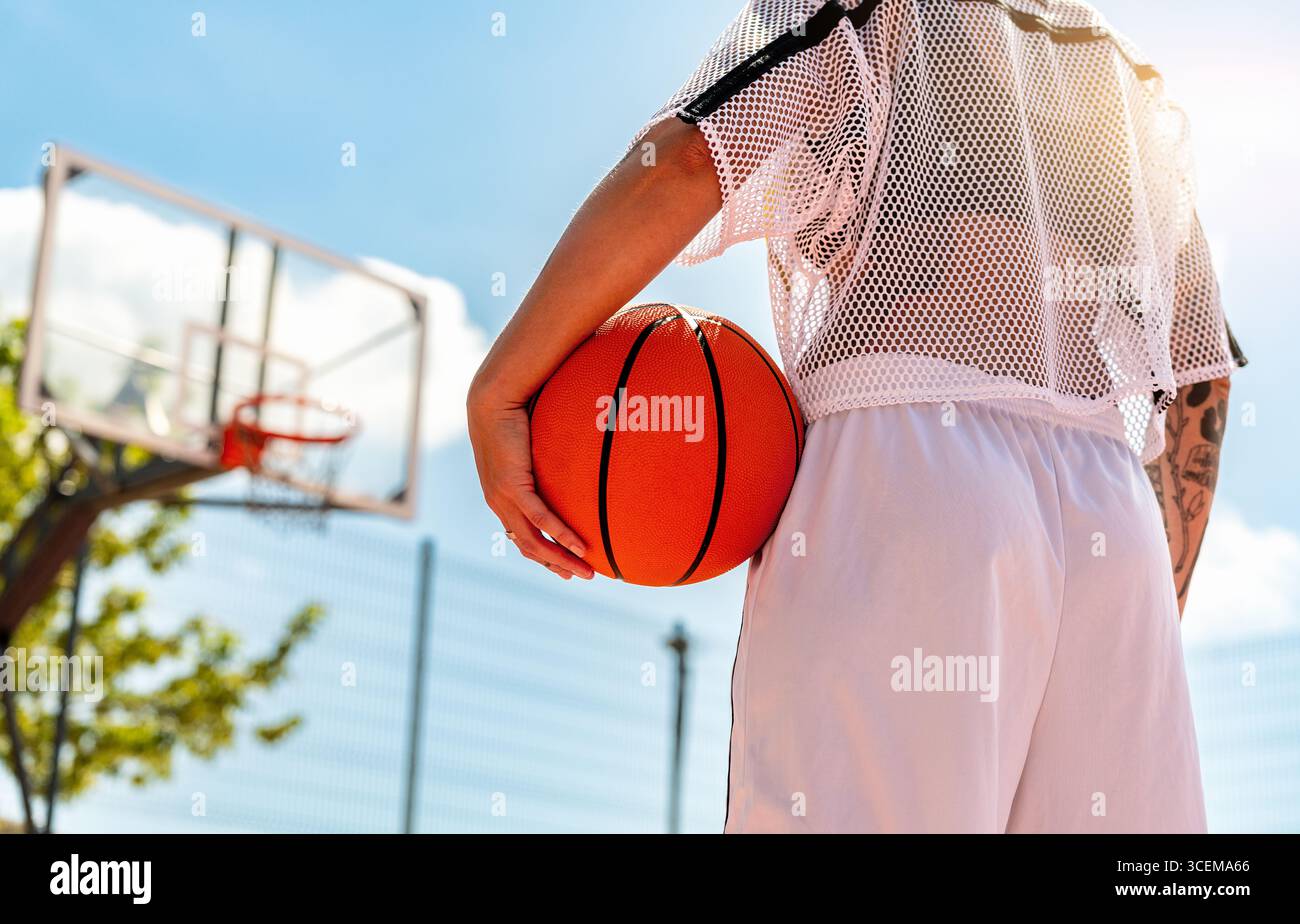 Atleta che tiene il pallacanestro sul campo da basket di strada Foto Stock