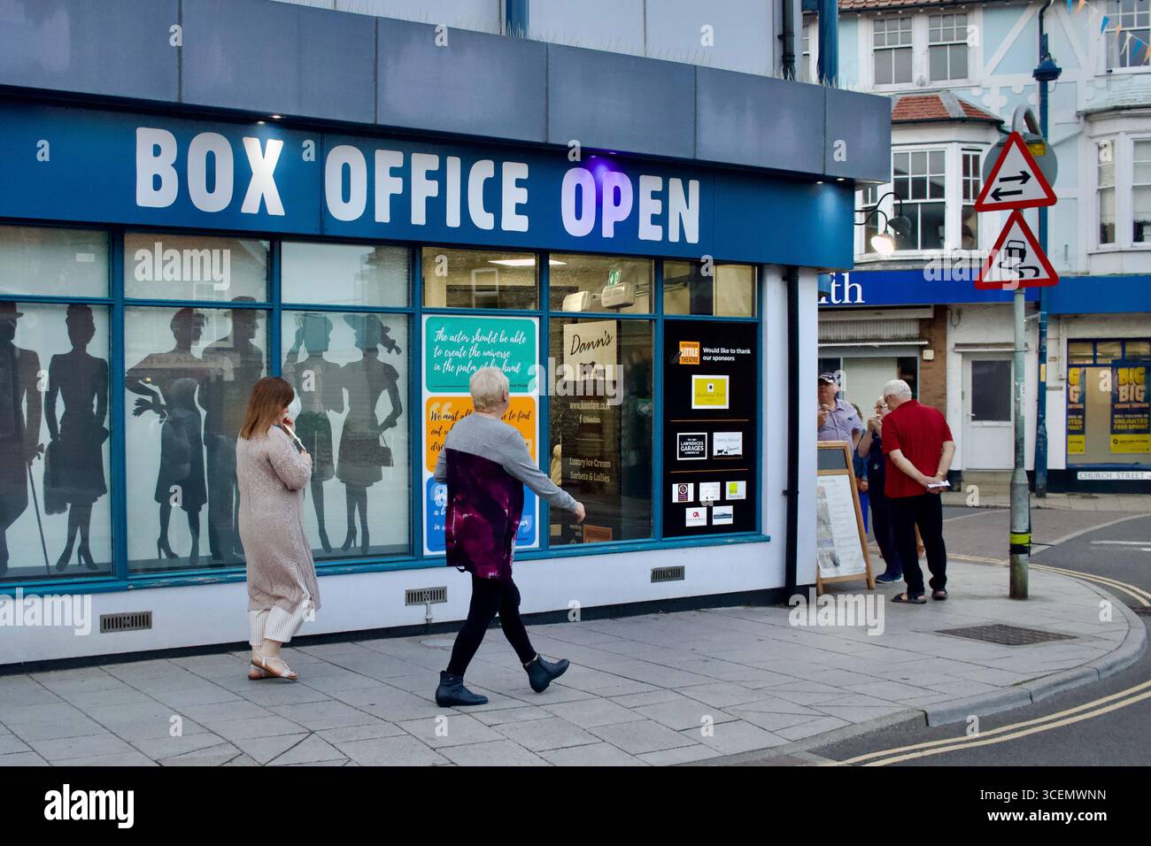 Due persone si vedono camminare davanti allo Sheringham Little Theatre, mentre altri si riuniscono all'ingresso - Sheringham, Norfolk, Inghilterra, 6 settembre 2024. Foto Stock