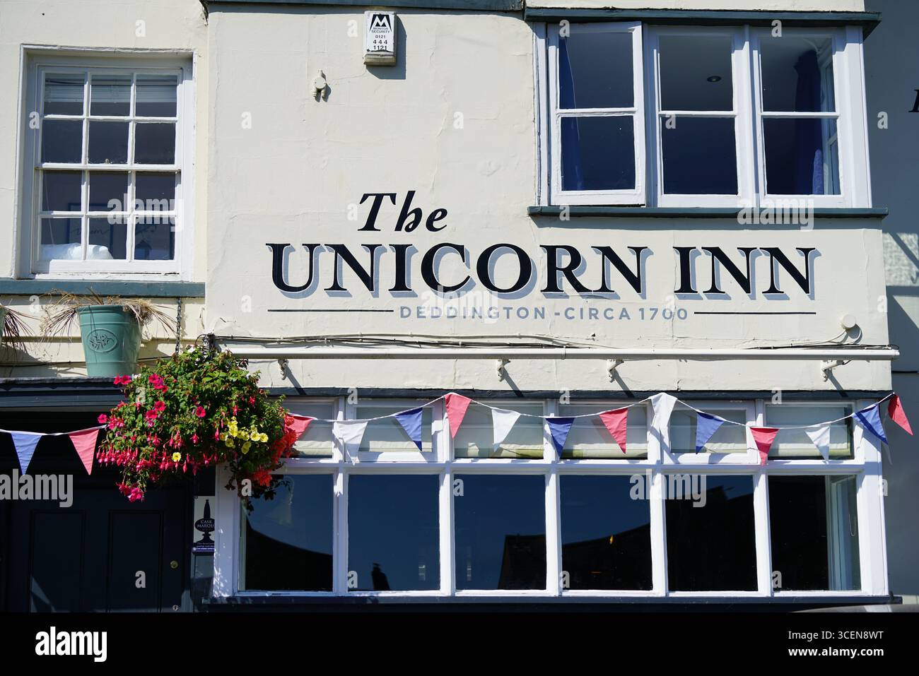 Affascinante facciata storica dell'hotel con fiori decorativi e mostra di Bunting festivo. Deddington, Inghilterra Foto Stock