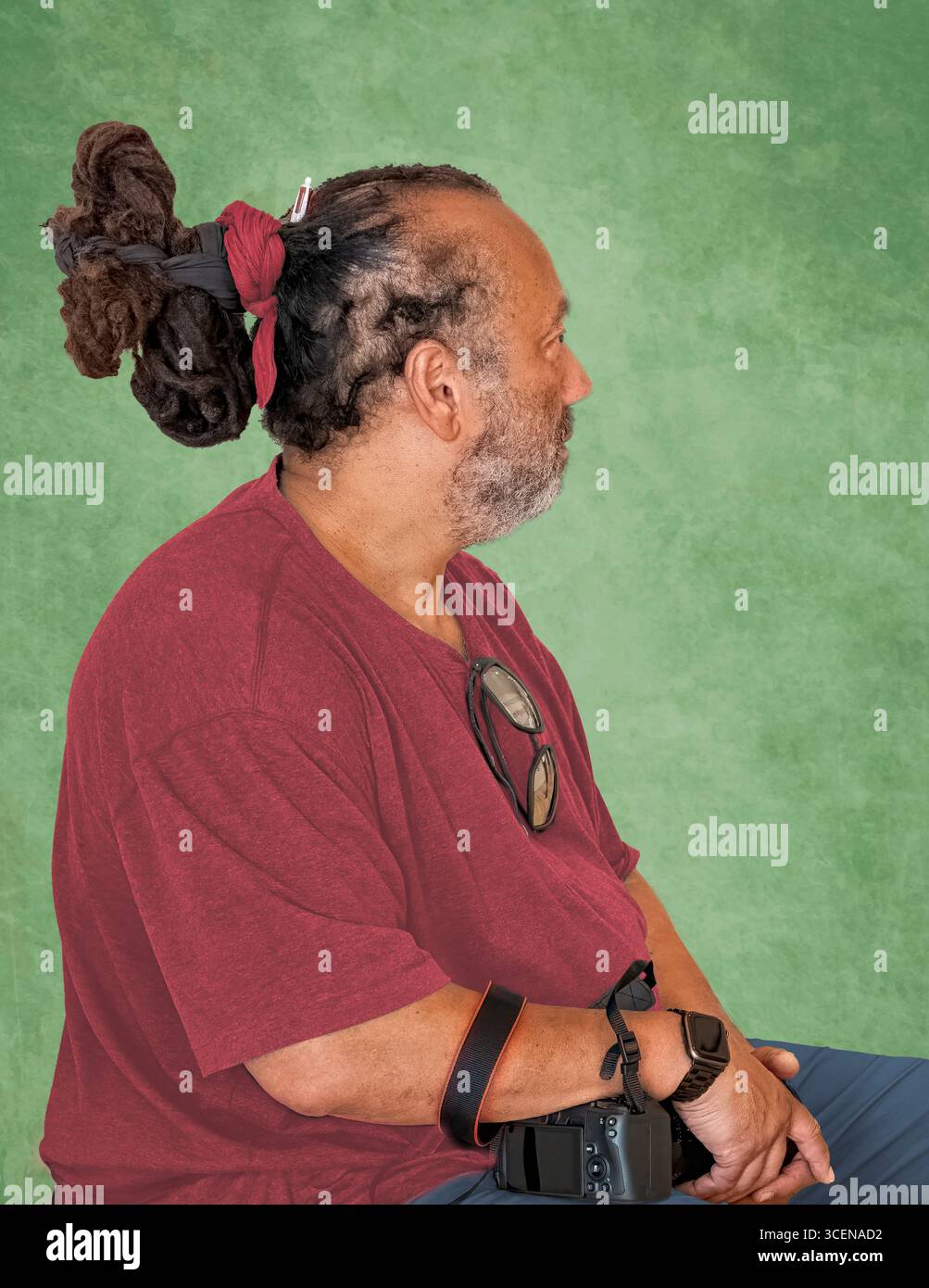 New York City - 18 giugno 2025: Ritratto di uomo dalla pelle scura con acconciatura afro riccia insolita, isolata su sfondo verde Foto Stock