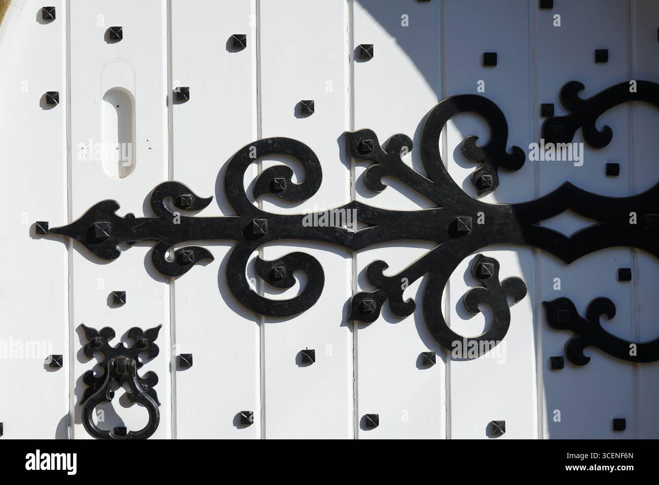 Dettagli in ferro decorato su porta in legno bianco dal design tradizionale. Adderbury, Inghilterra Foto Stock