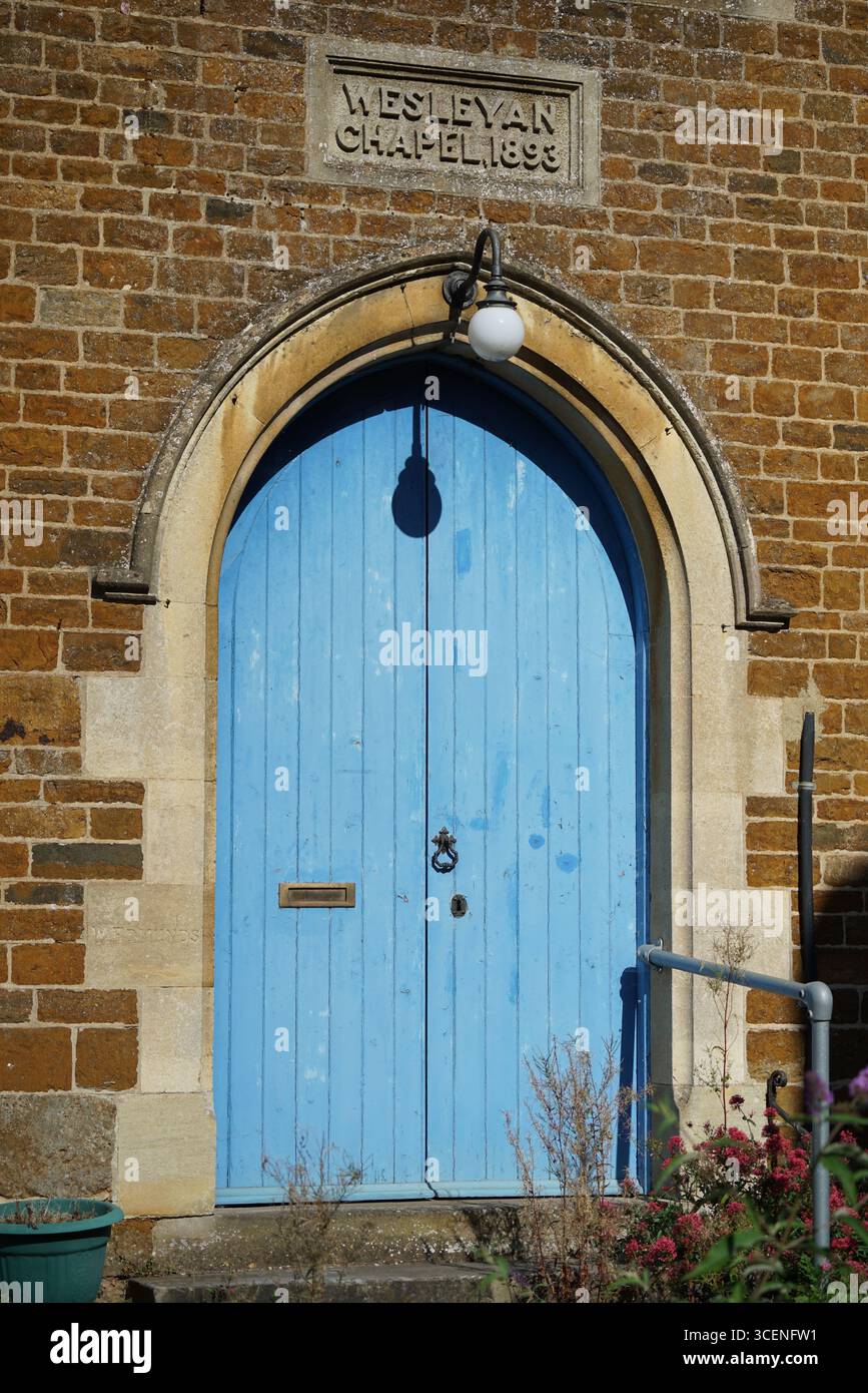 Storica porta blu della chiesa con mattoni e placca incisa. Adderbury, Inghilterra Foto Stock