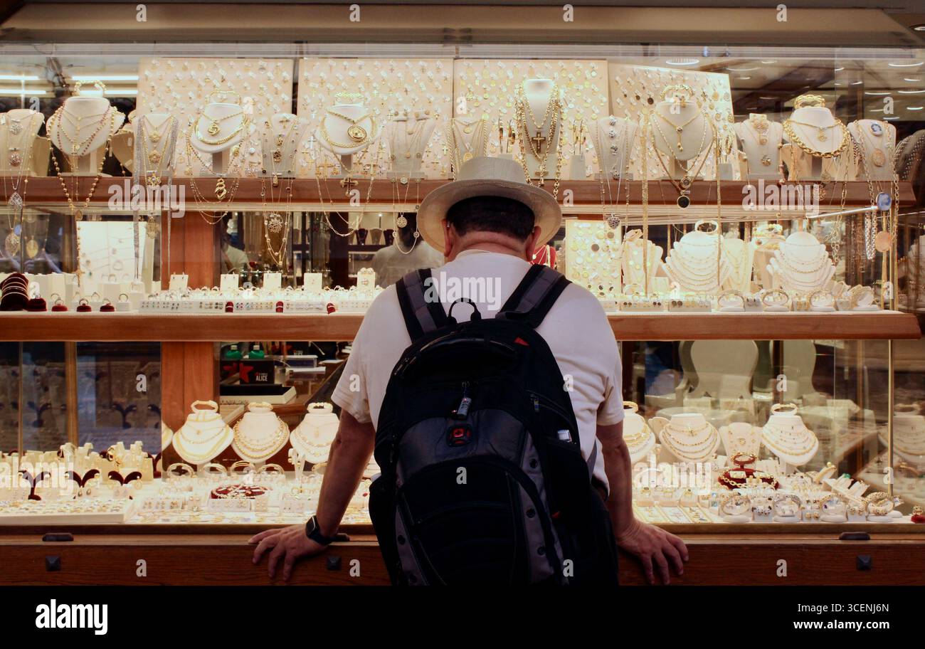 firenze firenze - un uomo con un cappello e uno zaino che guarda in una vetrina di gioielleria Foto Stock