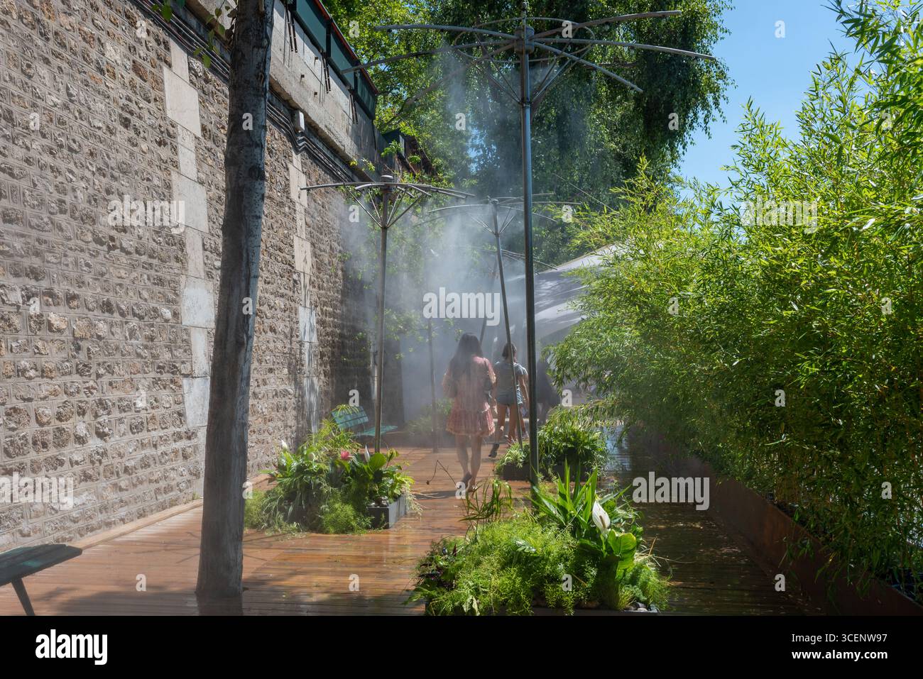 Persone che cercano di raffreddarsi sotto gli sprinkler a vapore durante il caldo estremo di Parigi. Irrigatori a vapore situati sulle rive della Senna Foto Stock