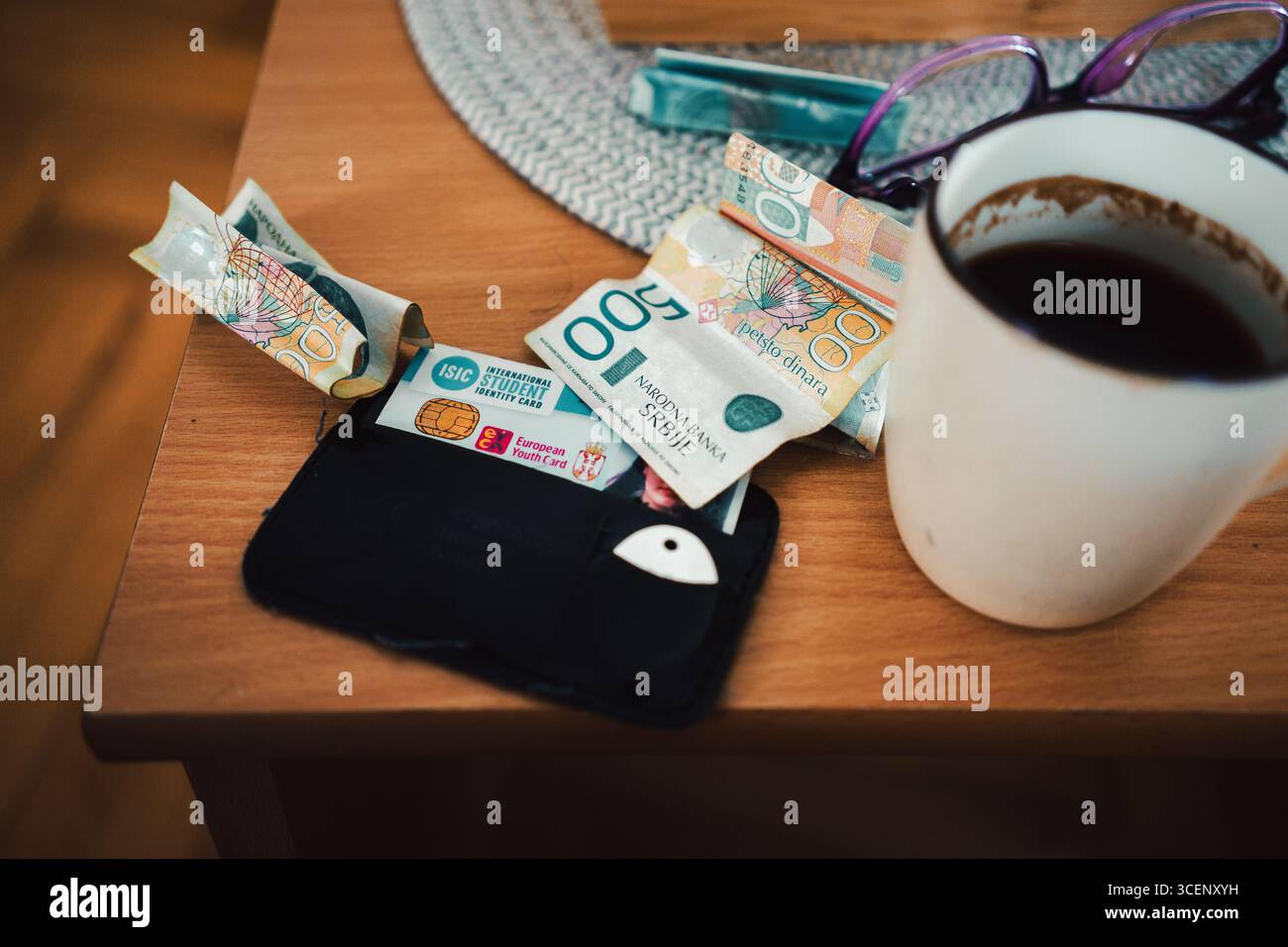 Cacak, Serbia - 16 agosto 2025: Carta d'identità dello studente, dinari e caffè sul tavolo, una scena della vita di uno studente in Serbia. Foto Stock