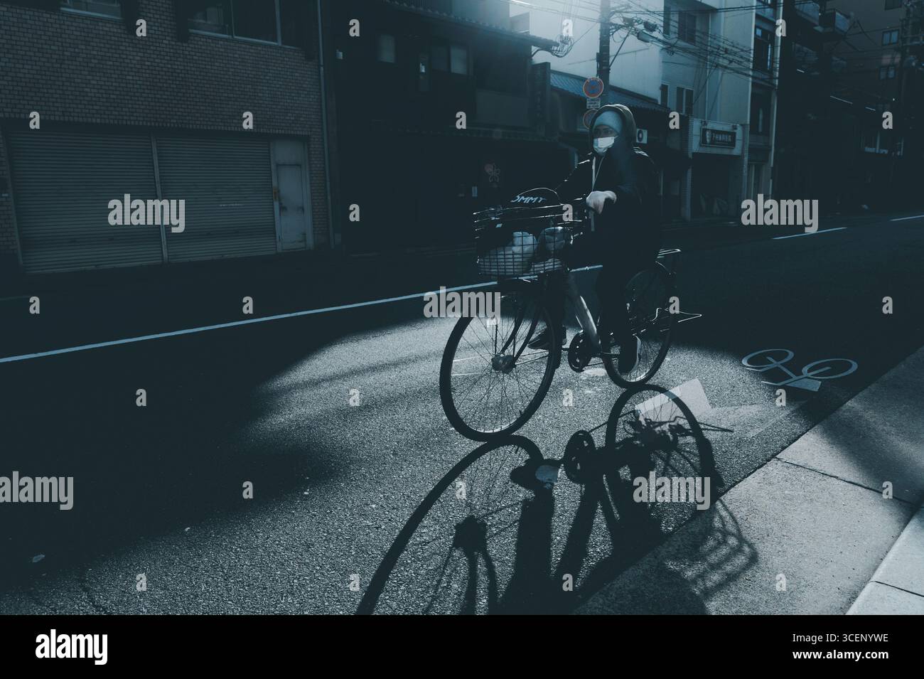Ciclista in maschera che cavalca intorno a Shimogyo Ward in una mattina d'inverno Foto Stock