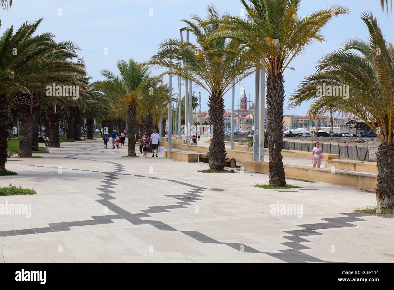 ALGHERO, ITALIA - 29 MAGGIO 2023: La gente visita la passeggiata costeggiata da palme sul lungomare nella città di Alghero, isola Sardegna, Italia. Foto Stock
