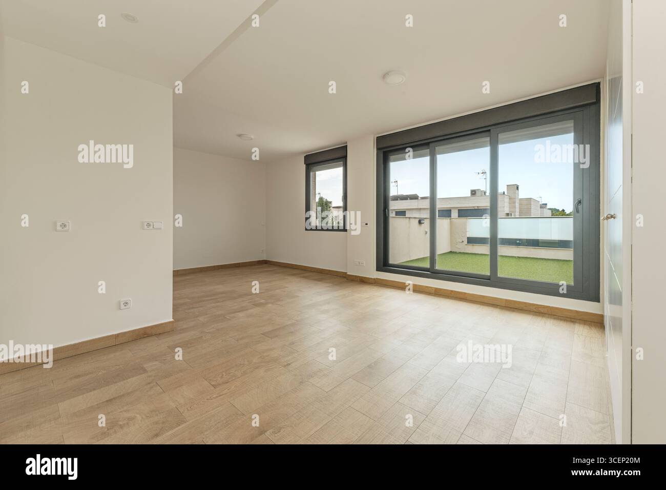 Ampio soggiorno contemporaneo con soffitto a doppia altezza, pareti bianche incontaminate e connessione visiva con il giardino esterno. Foto Stock