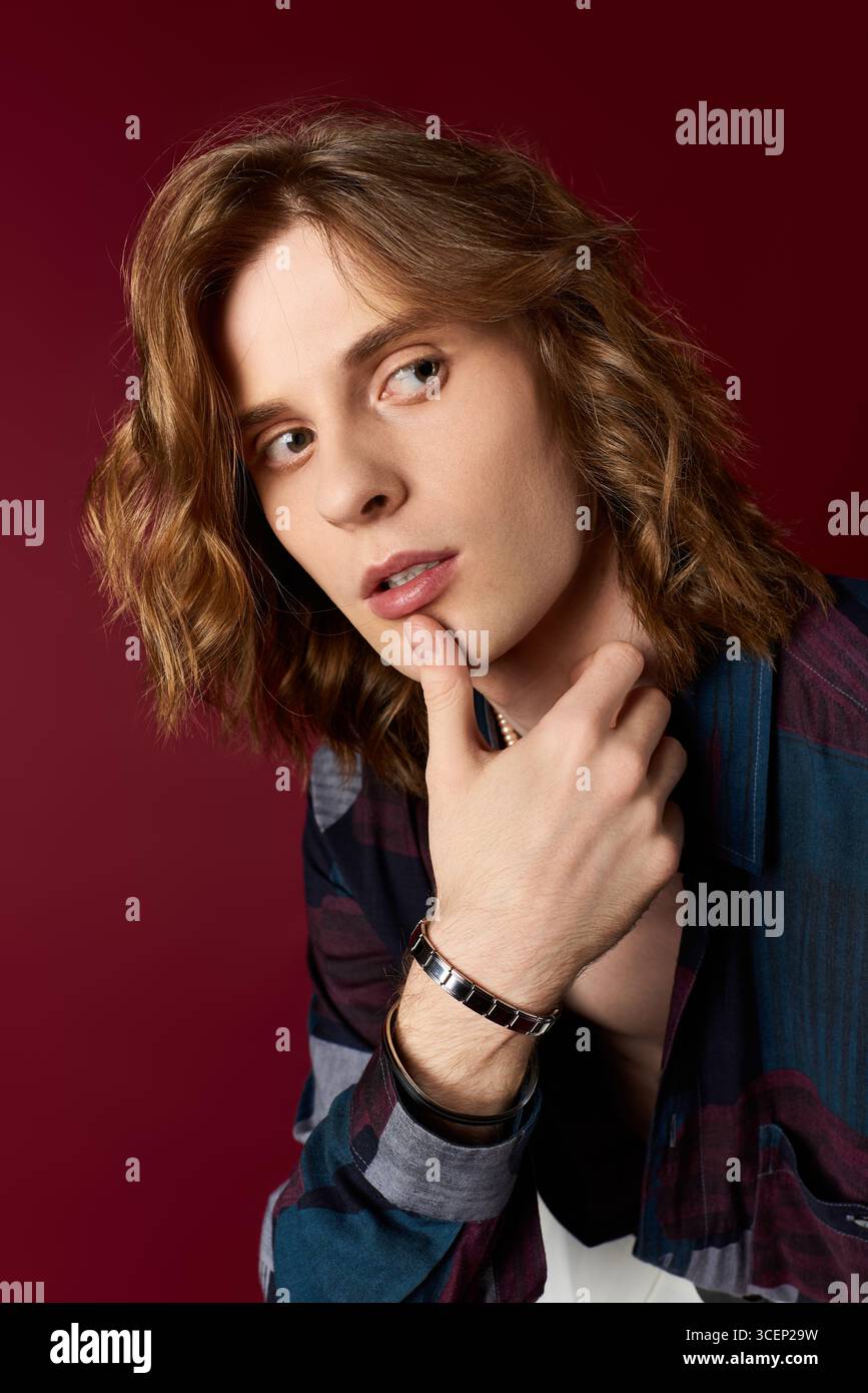 Un giovane uomo dalle onde lunghe si posa con cura, mostrando con stile il suo stile inconfondibile. Foto Stock