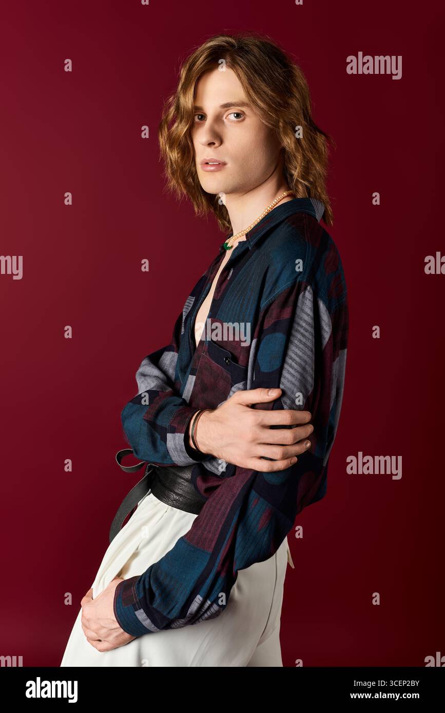 Un giovane uomo mostra il suo stile accattivante con uno sguardo accattivante, indossando abiti eleganti e alla moda. Foto Stock