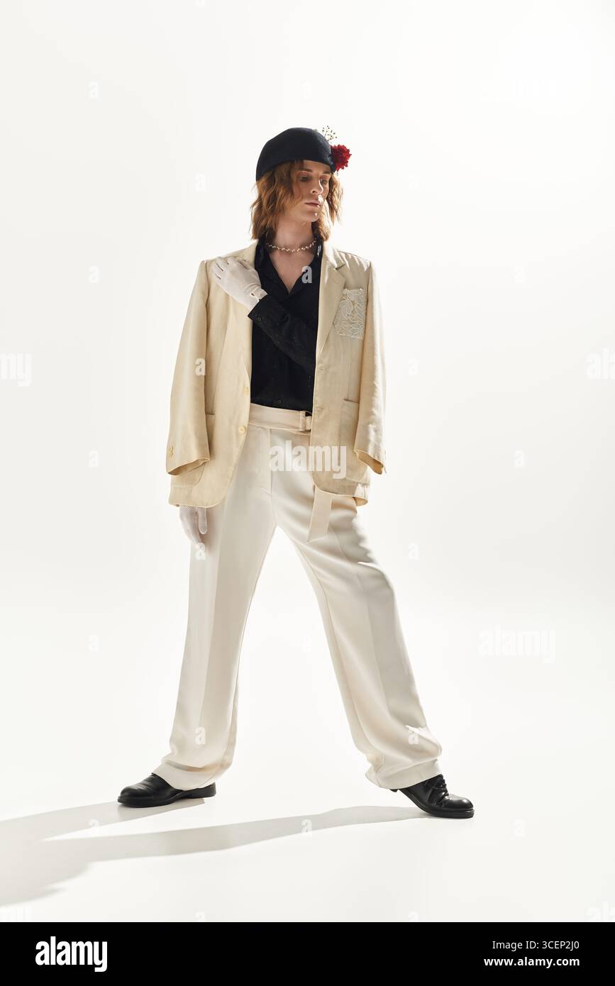 Un giovane e affascinante uomo con un abito elegante si posa con fiducia in uno spazio studio pulito e luminoso. Foto Stock