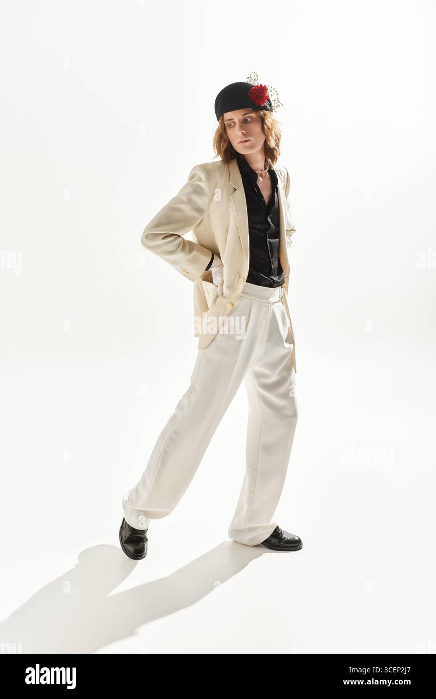 Un giovane uomo sicuro di sé affascina con un elegante abito bianco e una camicia nera, che mette in risalto il suo stile. Foto Stock