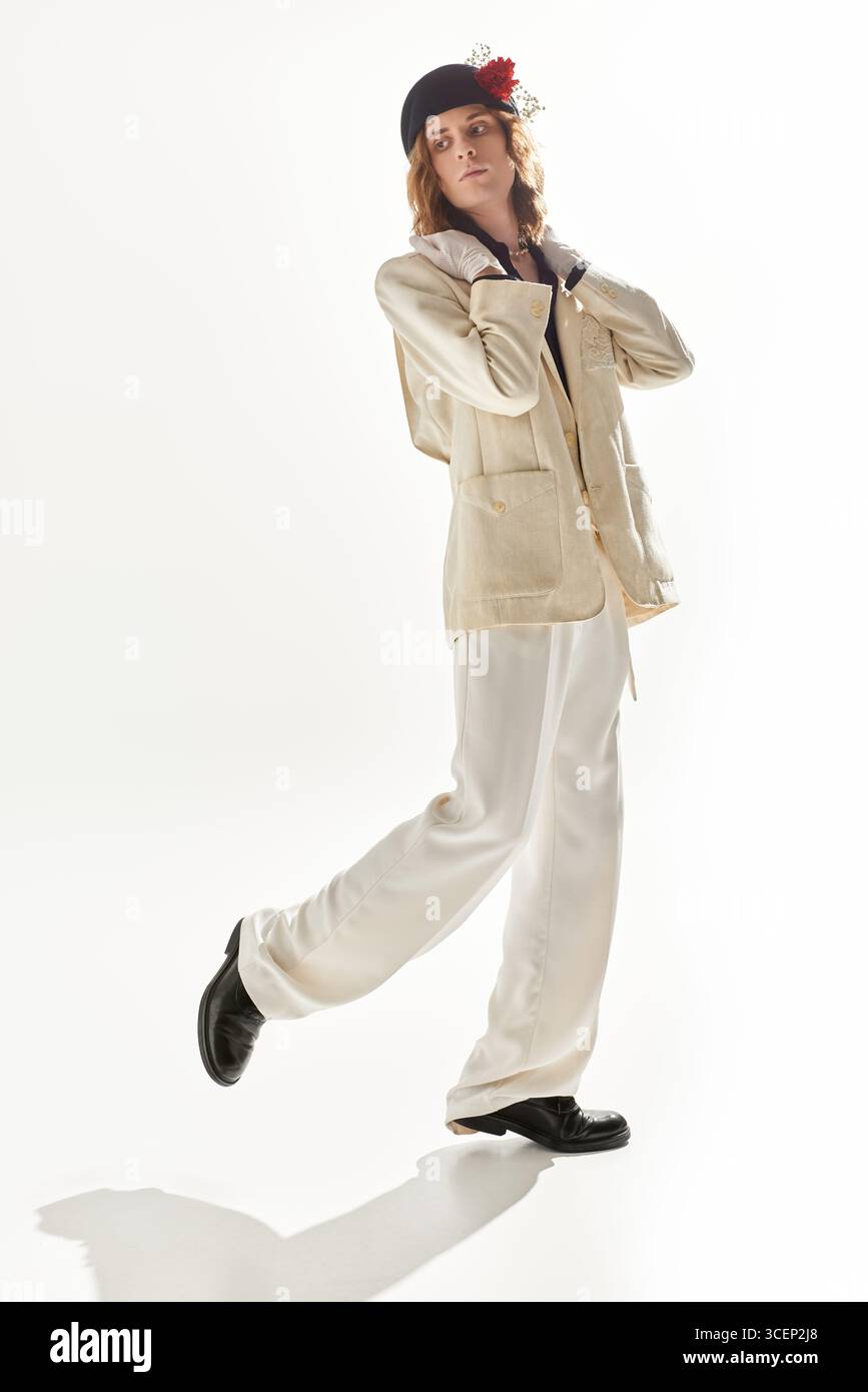 Posa sorprendente di una giovane figura maschile che mostra uno stile di moda unico su uno sfondo leggero. Foto Stock