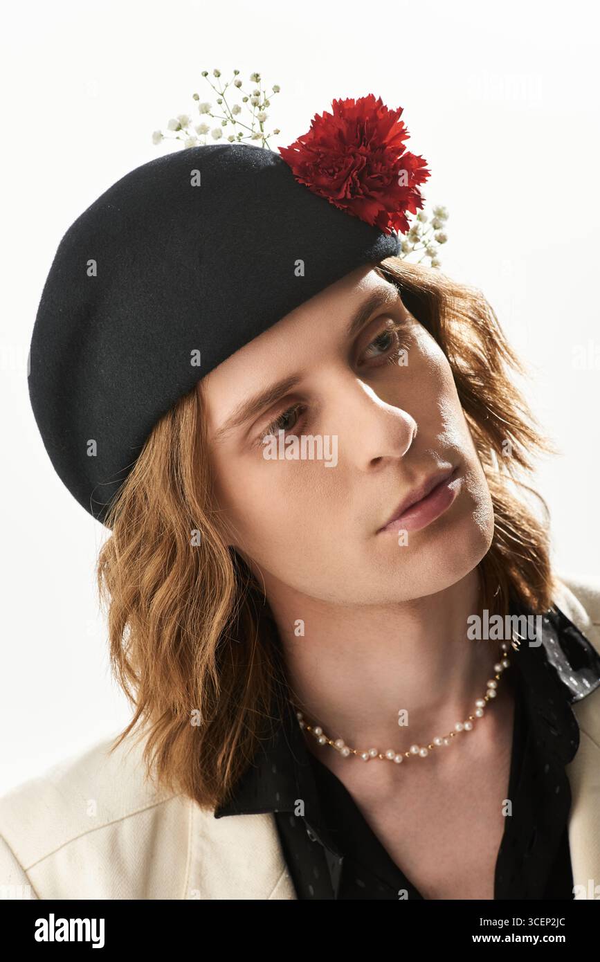 Un giovane uomo alla moda sfoggia un cappello nero floreale che sfoggia un look moderno e femminile. Foto Stock