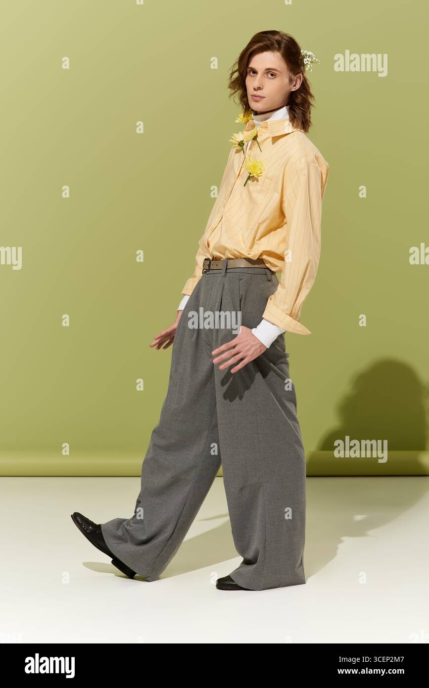 Un bel giovane uomo sfoggia uno stile trendy e femminile in un ambiente interno dai colori vivaci. Foto Stock