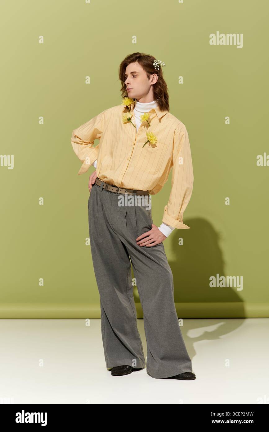Un bel giovane uomo si pone con sicurezza in uno stile di moda femminile floreale unico. Foto Stock