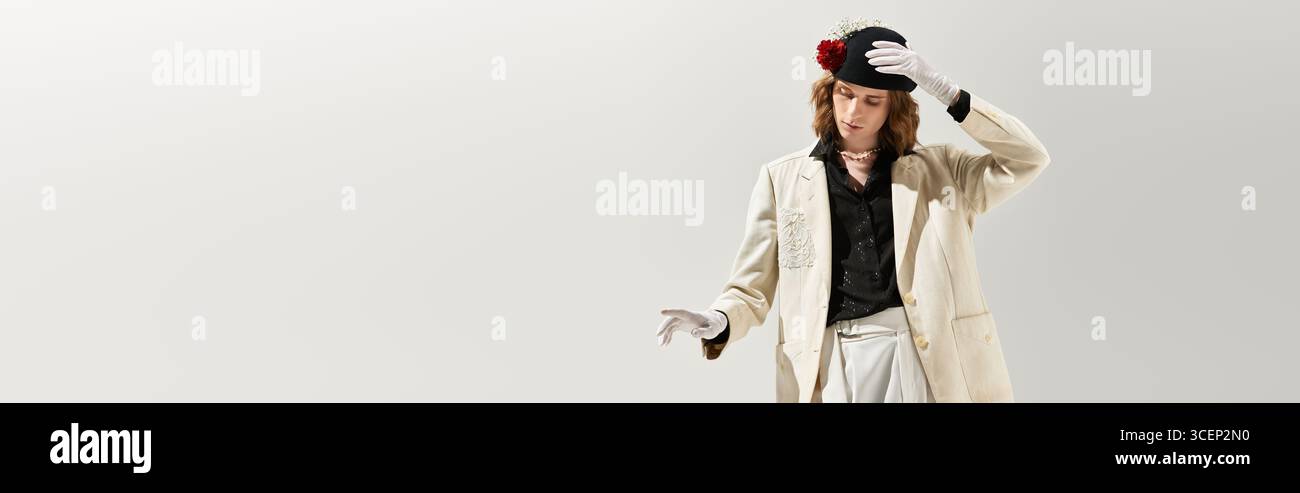 Un uomo giovane e femminile sfoggia la sua moda con un abbigliamento chic in uno spazio minimalista. Foto Stock