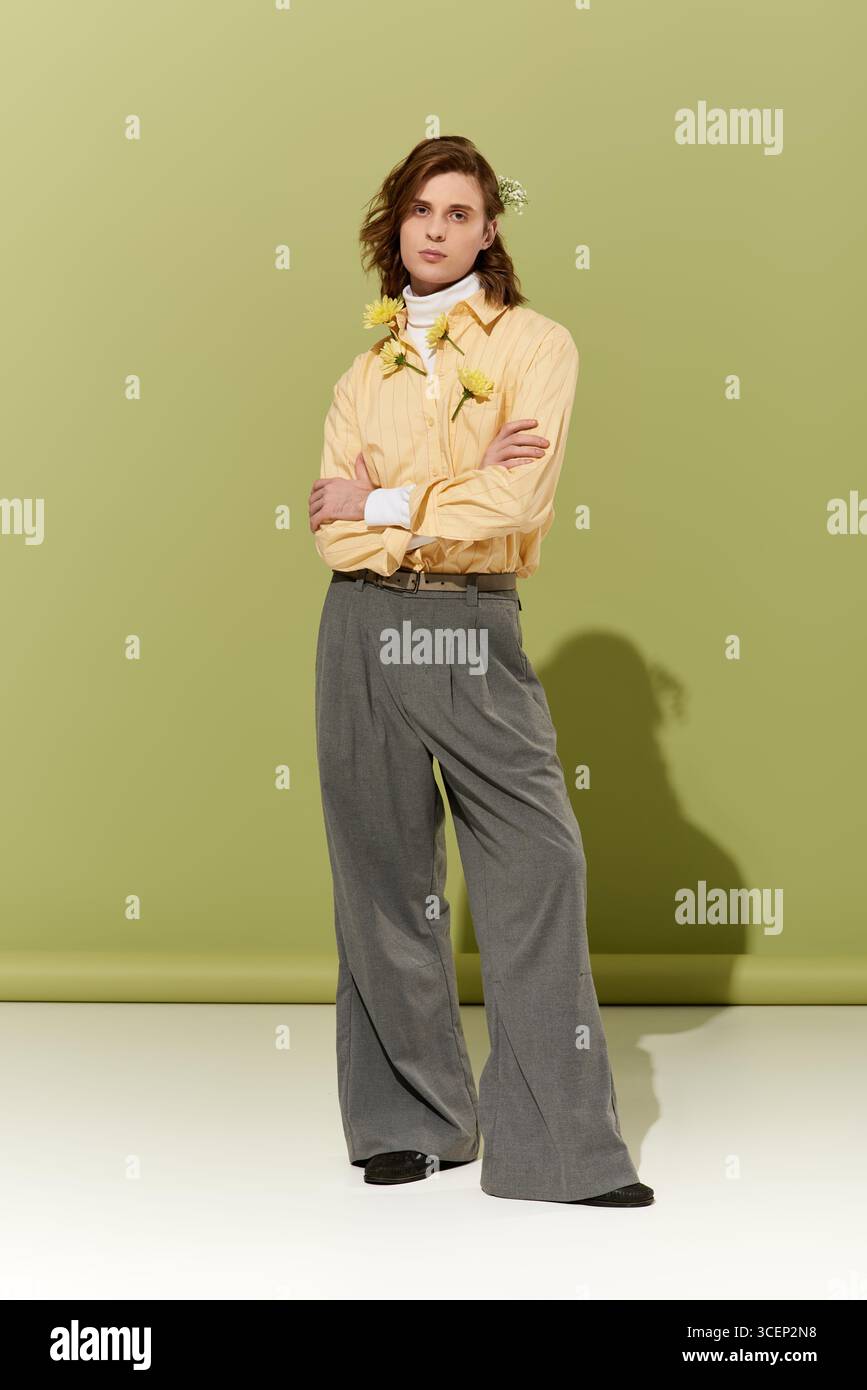 Un uomo giovane e bello affascina con un tocco femminile, mostrando stile moderno in una posa elegante. Foto Stock