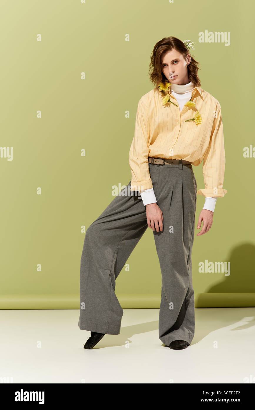 Un giovane elegante sfoggia con fiducia il suo esclusivo look femminile su un morbido sfondo verde. Foto Stock