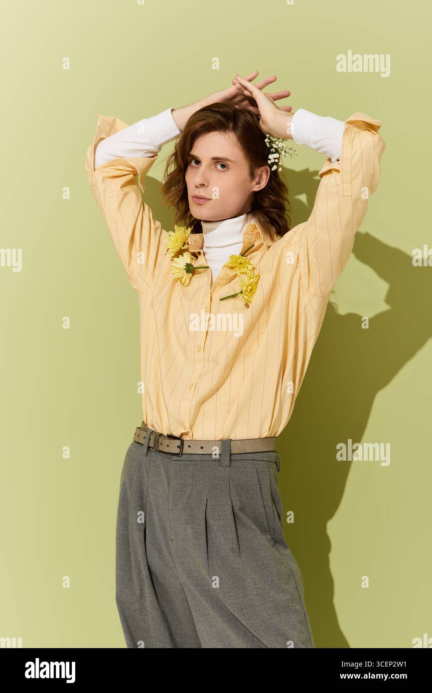 Un bel giovane uomo indossa un outfit chic con dettagli floreali che irradiano fiducia e stile. Foto Stock