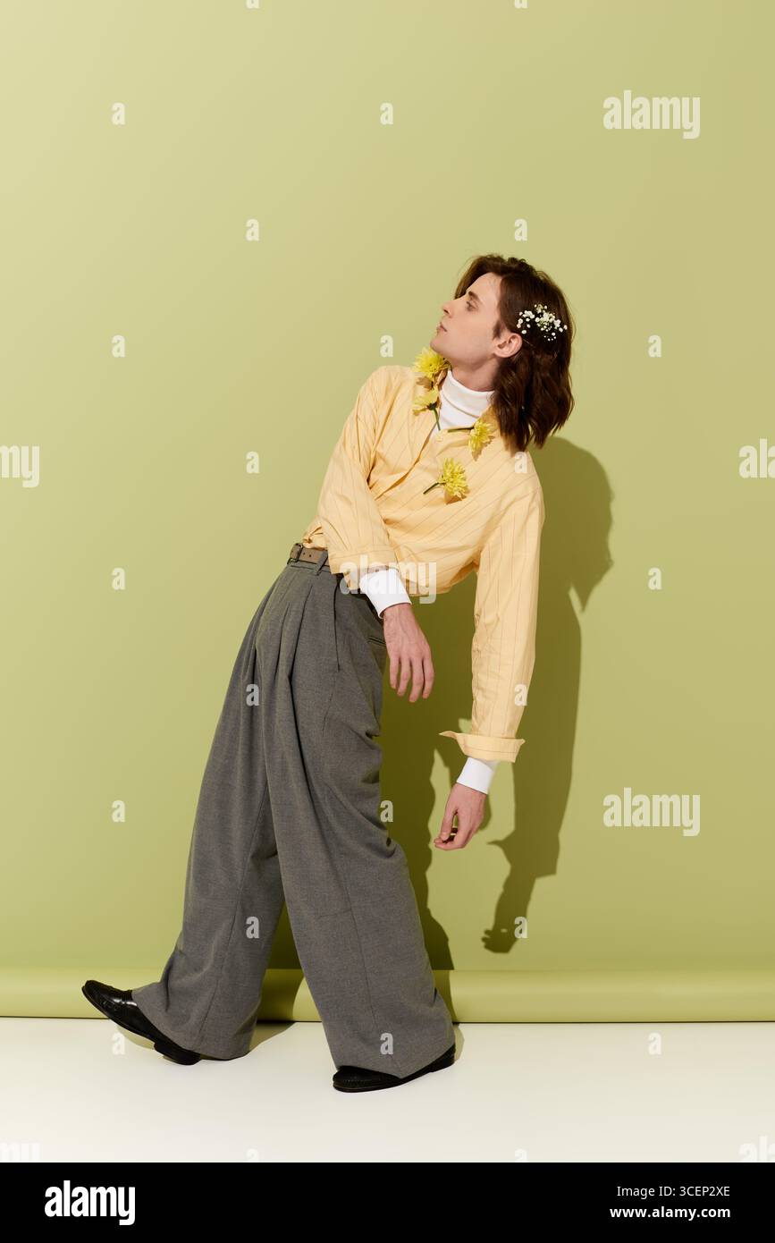Un giovane uomo sfoggia un look decisamente femminile con audaci scelte di moda su uno sfondo leggero. Foto Stock