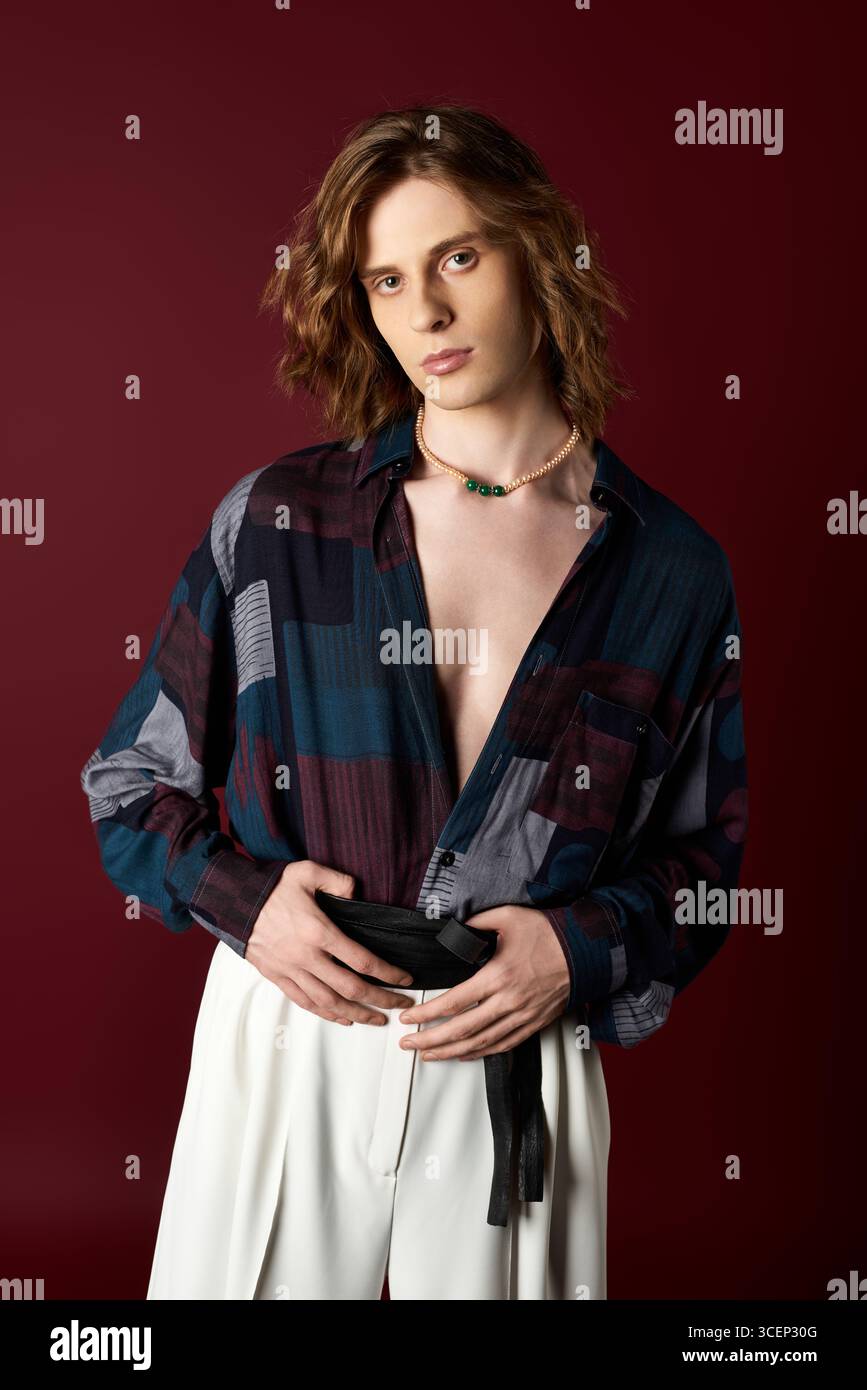 Un giovane uomo affascina per il suo stile femminile, indossando un outfit unico in un'atmosfera elegante. Foto Stock