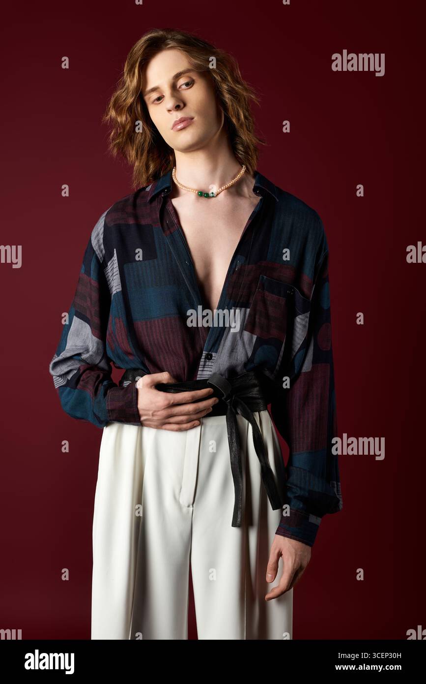 Un giovane uomo elegante indossa con sicurezza un outfit alla moda, che abbraccia un'estetica femminile. Foto Stock