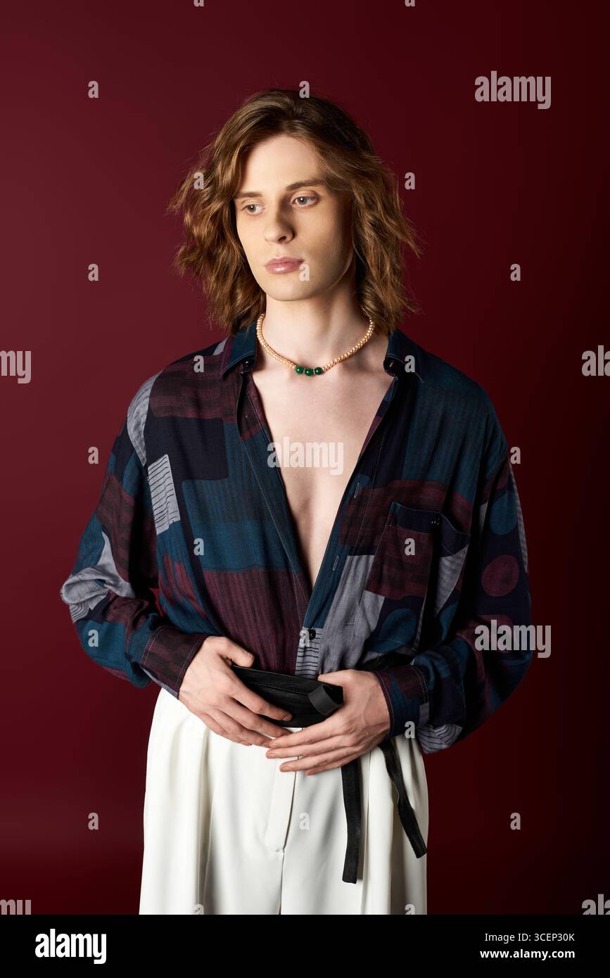 Indossato con un outfit alla moda, un giovane uomo affascinante cattura l'attenzione con stile e stile audaci. Foto Stock