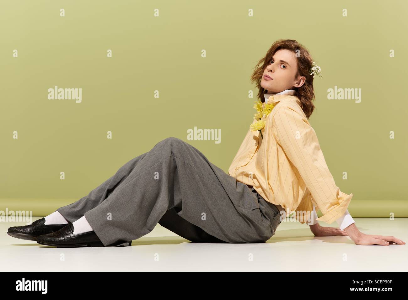 Indossando una camicia giallo chiaro e pantaloni larghi, posa graziosamente, mostrando il suo stile. Foto Stock