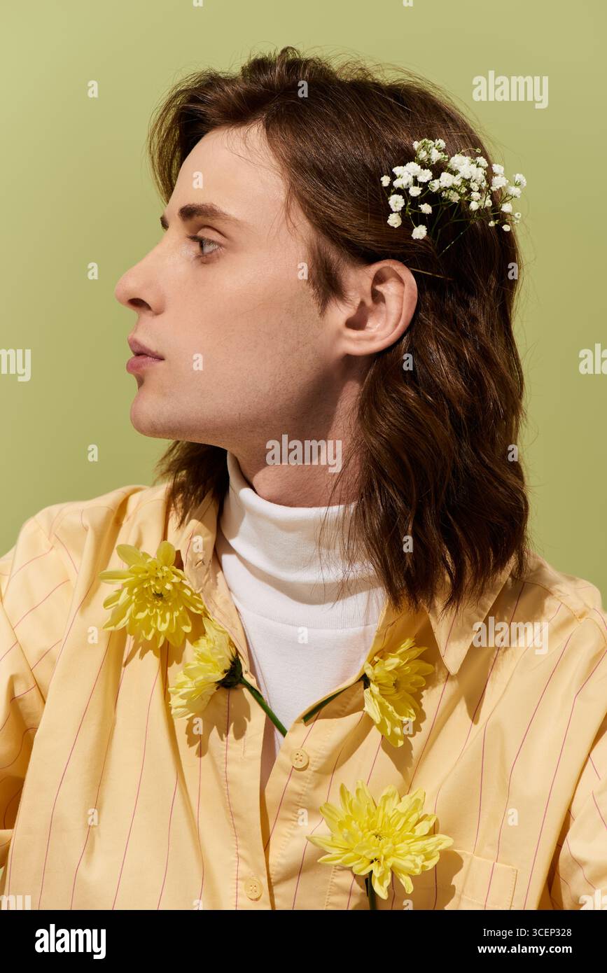 Un giovane uomo dai capelli lunghi sfoggia uno stile di moda femminile unico e sicuro. Foto Stock