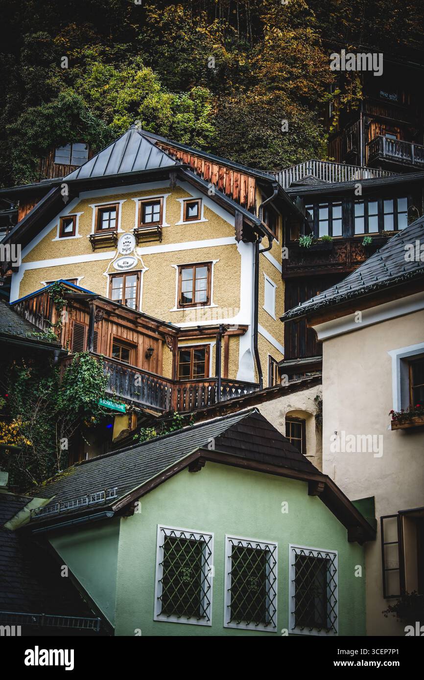 Vista di affascinanti case annidate contro una ripida collina boscosa, un arazzo di colori autunnali, con intricati dettagli architettonici, Hallstatt, Austria. Foto Stock